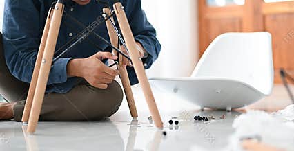 A young man assembling a chair in the house, D.I.Y Repair the chair for reuse