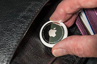 Apple AirTag being inserted into a leather purse