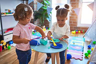 Adorable toddlers playing meals using plastic food and cutlery toy at kindergarten