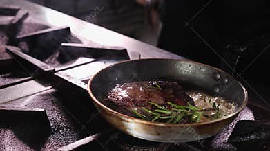 Beef steak fried in butter, chef handling the meat - close-up