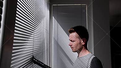 Man cleaning dust from window blind by vacuum cleaner at home