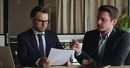 Happy two confident businessmen discussing paper agreement in office.
