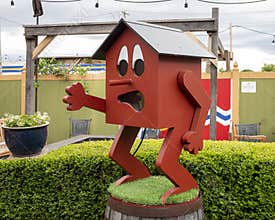 Red house with cartoon human face, arms, and legs standing outside in Saint Louis, Missouri.