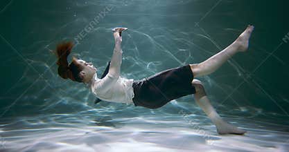 Stress disorder. Young business woman sinks under water with smart phone in hand slow motion. Information overload.