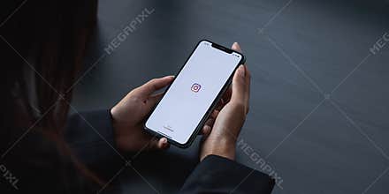 CHIANG MAI, THAILAND - APR 6 2021: Woman hand holding iphone with logo of instagram application. Instagram is largest