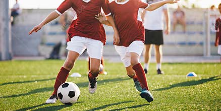 Two young football players running the ball. Soccer players compete in the training games