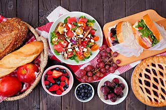 Summer picnic food table scene top view over a wood background.