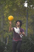 Juggler performs an equilibrist number playing with skittles and ball