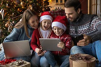 Overjoyed family couple with kids watching funny Christmas cartoons.
