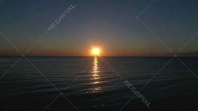 Beautiful sunset over the sea. The sun is reflected in the water. Fabulous sunset landscape by the ocean. Flight over