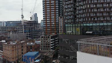 Ascending footage of construction of new building in Shoreditch district. Modern tall skyscrapers around. London, UK