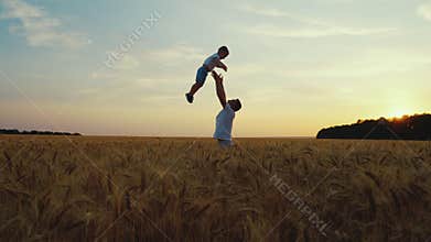 Father throwing son up in the air in field