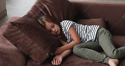 Tired tranquil little cute kid girl sleeping on comfortable sofa.