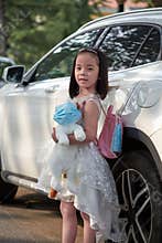 Girl with backpack, doll cat and masks, travel plan and carry-on.