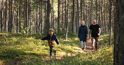 Happy young family enjoying walk in forest. running children