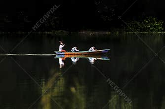 Traditional wooden boat passes silently in the tranquil lake environment