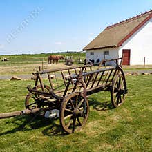 Country house with with horses in the distance and the old cart
