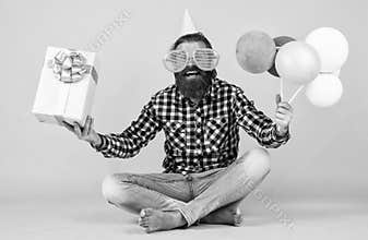 funny brutal bearded man wear checkered shirt having lush beard and moustache hold party balloons and present box