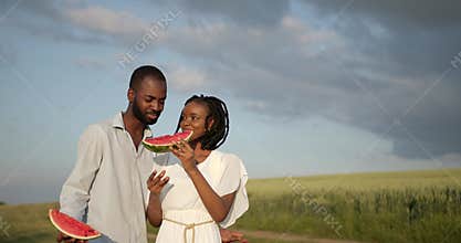 Black couple with watermelon on a meadow