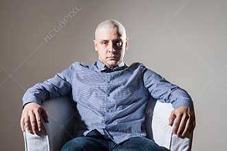 Bold man sitting in a chair