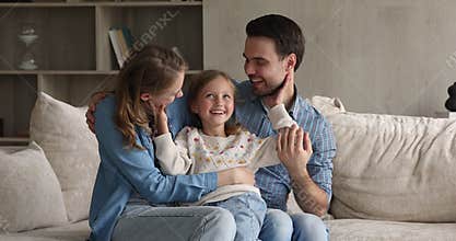 Affectionate little girl cuddle beloved mom and dad at home