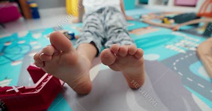Cute children foot closeup moving fingers sitting in kid room on evening
