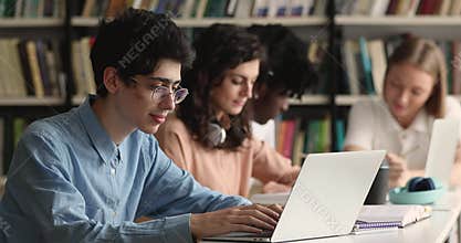 Student guy sit at table preparing for exams using laptop