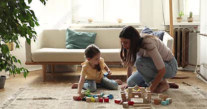 Young nanny play wooden constructor set with little girl preschooler