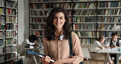 Portrait of attractive student girl posing standing in campus library