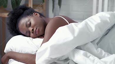 Serene african american woman sleeping waking up in comfortable bed lying on soft pillow orthopedic mattress, calm young