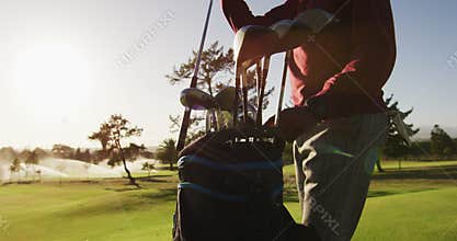 Video of midsection of african american man putting golf clubs into bag on golf field