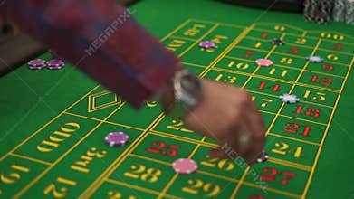 Top view hands of men betting with chips on a gaming roulette table in a casino