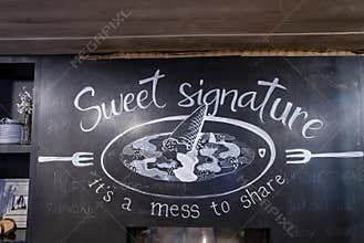 Close-up of name plate with text and drawing against wall at restaurant