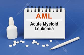 On a blue background, a pen, tablets and a notepad with the inscription - AML Acute Myeloid Leukemia