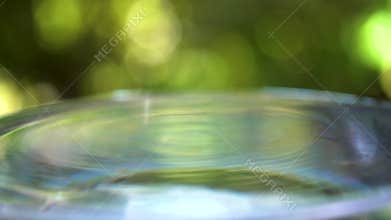 Droplet of water with ripples, in green nature