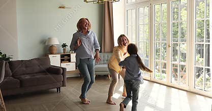 Overjoyed 3 female generations dance barefoot on warm wooden floor