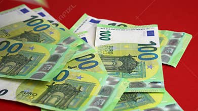 Money falling on table. Dropping lot of one hundred Euro paper banknotes on red paper background