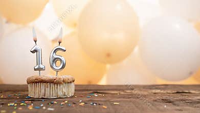 Happy birthday card with candle number 16 in a cupcake against the background of balloons. Copy space happy birthday for sixteen