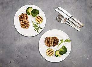 Turkey or chicken cutlets meatballs zucchini and broccoli in white plates on a grey background  top view. Healthy balanced food