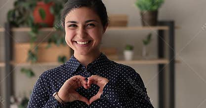 Happy millennial kind indian ethnicity woman showing heart symbol.