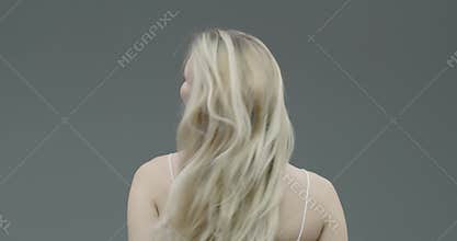 Pretty young blond female with long hair take off scrunchie, let down hair during everyday beauty routine, back view