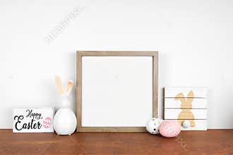 Mock up square wood frame with shabby chic Easter decorations on a wood shelf against a white wall