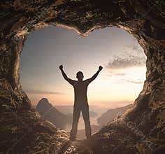 Ethereal Heart Shaped Cave Opening with Silhouette of Triumphant Explorer at Golden Hour