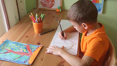 Boy drawing tree sitting bu desk