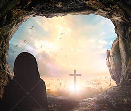 Silhouette Praying Inside Cave Looking Toward Cross and Radiant Sunrise Sky