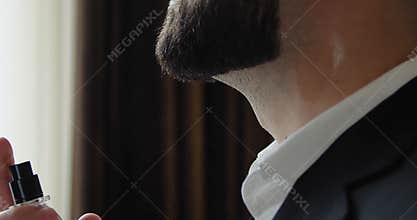Anonymous man spraying fragrance in extreme slow motion, with scent particles to wet skin. Close up