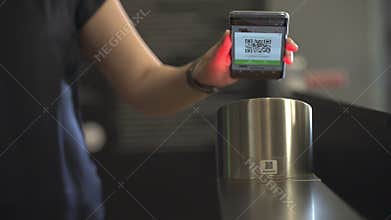 Woman using her QR code on her phone to open the entrance gate