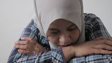 Sad unhappy lonely and depressed young Asian muslim woman crouching and crying at home. Stress exhausted feeling down expression