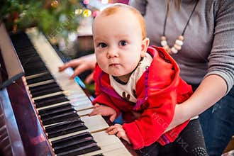 Christmas eve party  baby boy playing piano with his mother