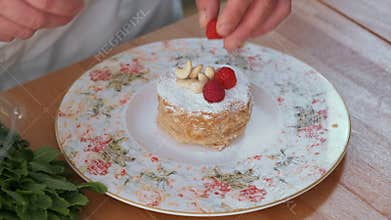 Chef decorating honey cake with raspberry and cashew